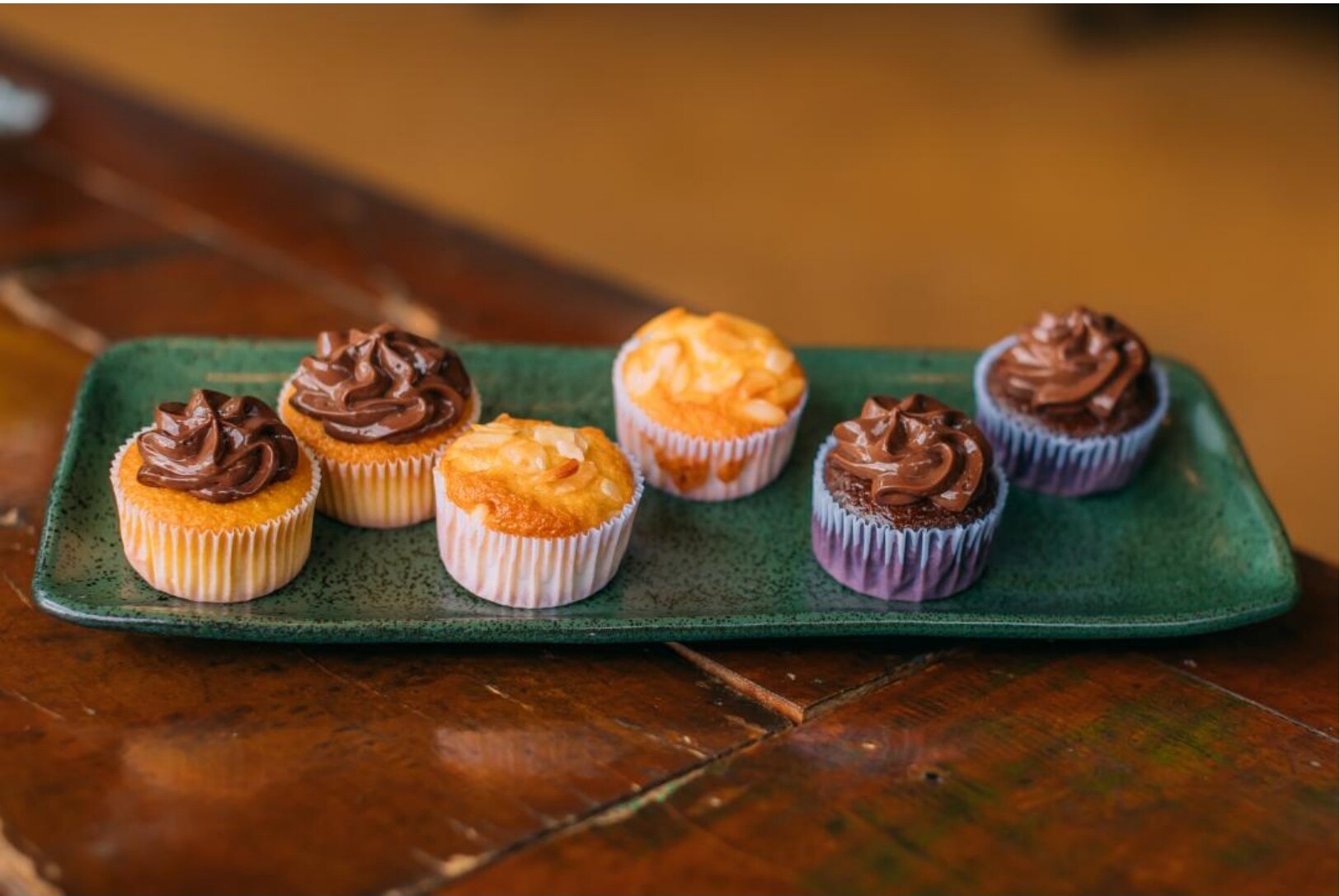 Bandeja verde com mini cupcakes de chocolate e baunilha